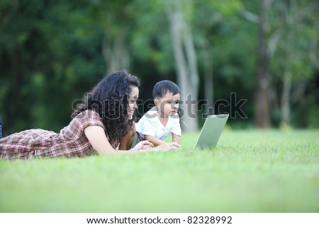 women holding baby and typing on laptop computer in garden