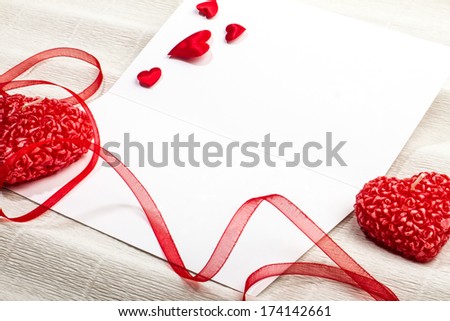 Empty postcard with heart-shaped candles, red ribbon and small fabric hearts. Valentine day design.