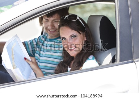 pair of travelers by the car search a route on the map. girl holds a road map