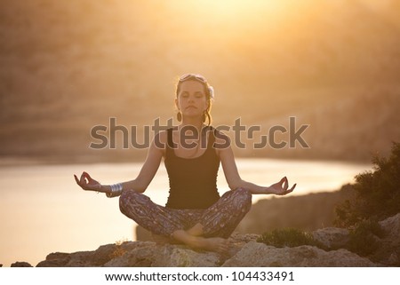 girl meditating in sunset. girl sitting on a rock in the lotus pose