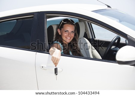 Young female driving happy for her new car or driver license. Woman driver showing car key out the window