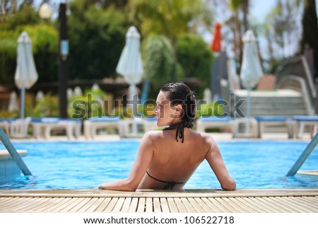 the girl on vacation costs a back half in water in the pool and having turned back smiles