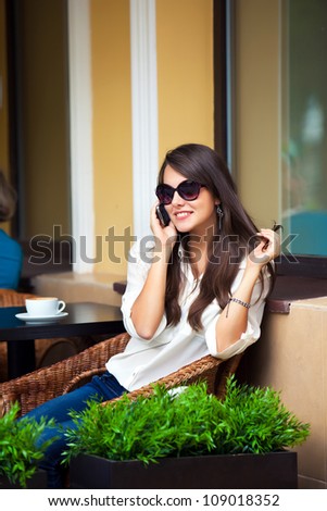 young attractive girl talking on a cell phone in a summer cafe