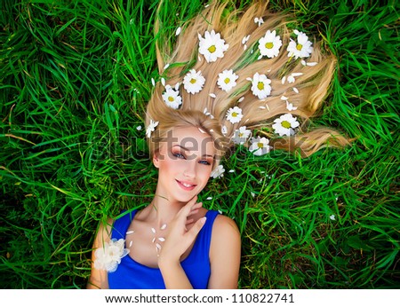 Beautiful woman lying in the green grass with a flowers of daisies in her hair