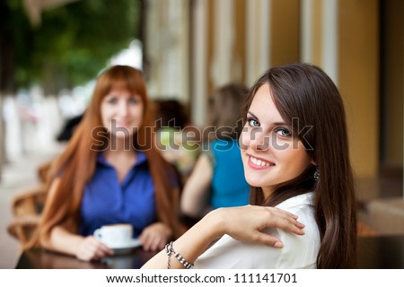 two girl friends drinking coffee at breakfast or dinner at an outdoor cafe
