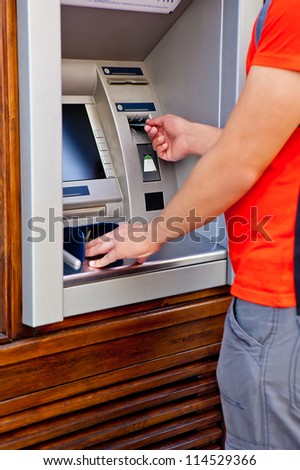 Man tourist at puts bank card into the ATM