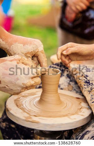 The hands of a potter creating an earthen jar on the circle