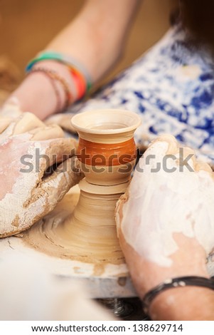 The hands of a potter creating an earthen jar on the circle