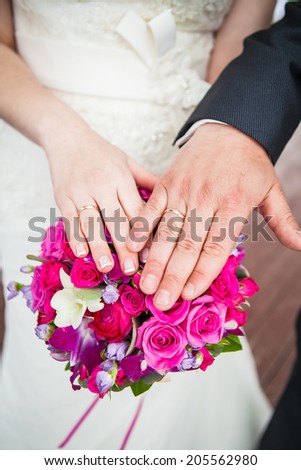 Wedding flowers and hands of a newly-married couple with wedding rings