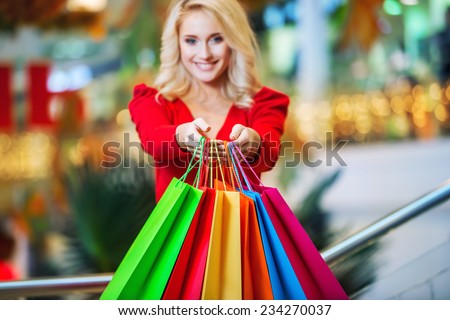 Young woman with colored shopping bags in the shopping mall on sales. Focus on the hands and bags