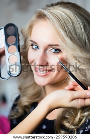 Woman with make up brush and eye shadows palette