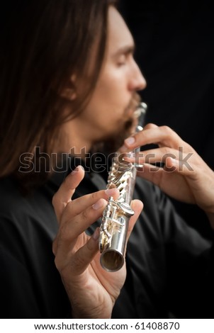 Young man in black playing metal flute