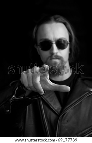 a rock man in sunglasses pointing his finger to the viewer, focus on finger