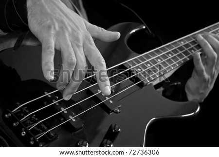 electrical bass guitar in male hands, closeup, black and white