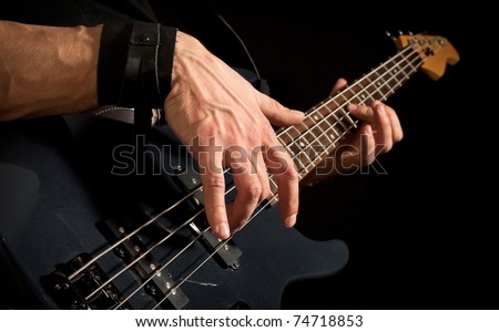 male hands playing on electrical bass guitar