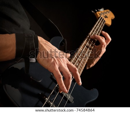 electrical bass guitar in male hands, black background