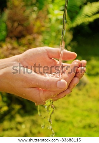 stream of water pouring on hands, green background