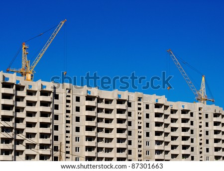 yellow lifting cranes over new unfinished apartment house