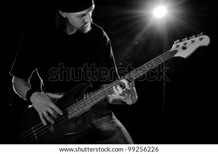rock musician, playing on bass guitar, black and white