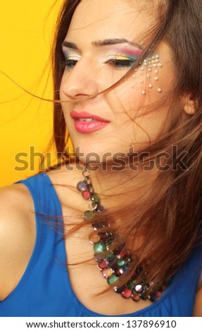 Close-up of beautiful female face with colorful make-up and lips wearing jewelry and windy hair