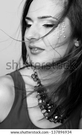 Black and white portrait of a beautiful female face with colorful make-up and lips wearing jewelry and windy hair
