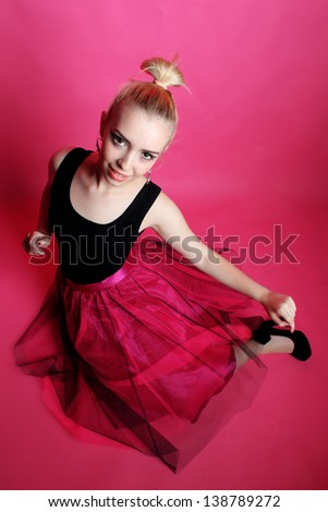 Young lady posing and dancing in the studio on a pink background