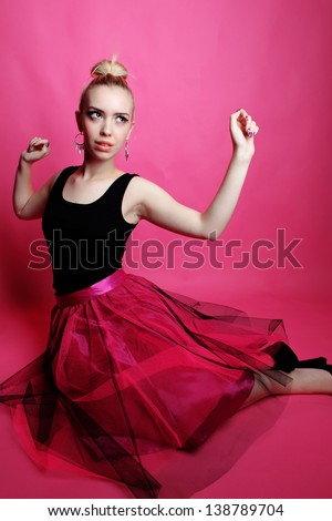 Young lady posing and dancing in the studio on a pink background