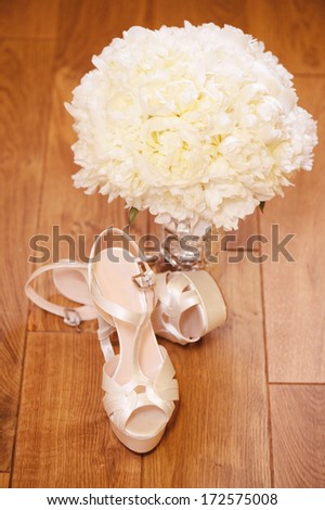 Elegant wedding shoes with beautiful bouquet on the floor