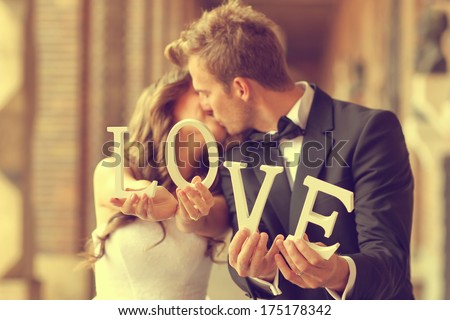 Happy bride and groom holding LOVE letters
