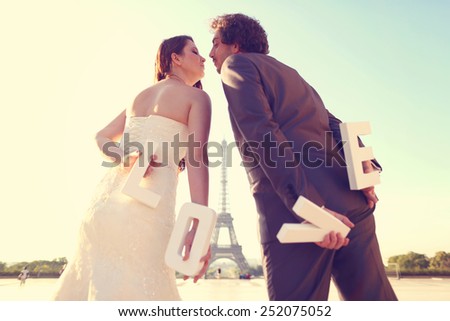 Bride and groom holding LOVE letters in their hand in Paris, France