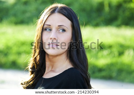 Young and beautiful lady posing outside and looking behind her left shoulder