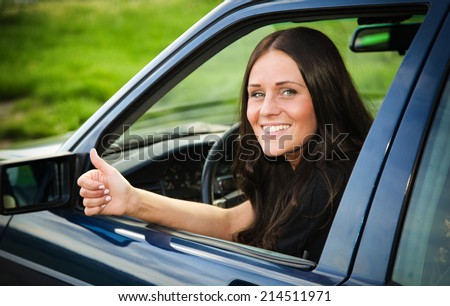 Young and beautiful lady showing thumb-up from her older used car