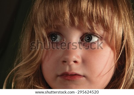 Scared look of very young girl with face expression over dark background