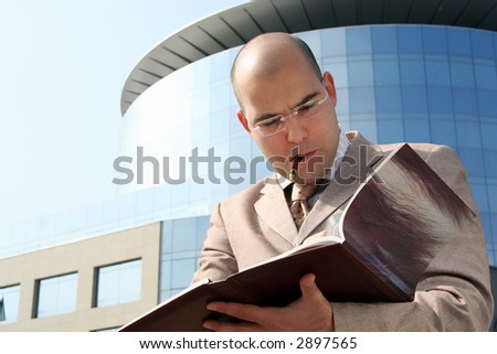 Business man in the middle of writing up the business building holding pen in mouth