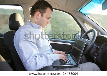 Young businessman in the car working on notebook during driving
