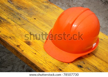 Orange hard hat (construction helmet) on wooden table on construction site