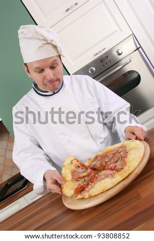 Pizza chef holding slice of pizza and with face expression shows that he is very hungry