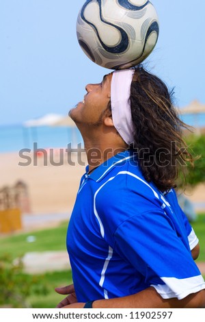 A professional football player holds a master class games head on the beach. A man of Hispanic ethnic.
