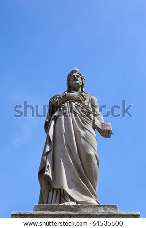 Photo sculpture men on the podium with a Bible in his hand on a blue sky background.