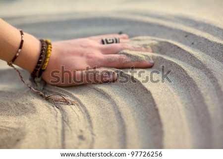 Prints on the sandy beach of the women\'s hands with rope bracelets