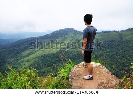 A Man stand on the cliff\'s edge look over the clear sky