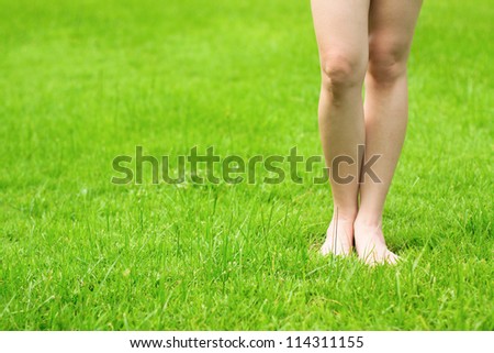 Woman\'s legs stand on fresh green grass