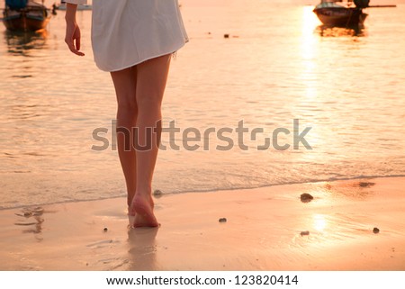 Young woman\' s legs walking on the beach with sunset