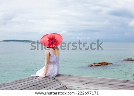 Young lady sit on the wooden pier and see the beautiful sea