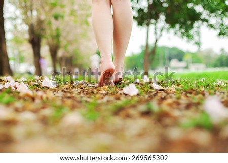 Woman legs walk over green grass.