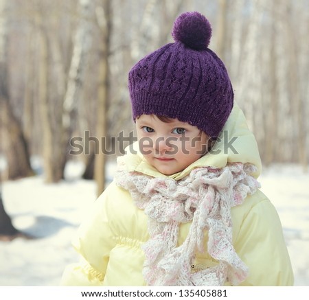 Happy baby girl in hat outdoor winter background. closeup portrait