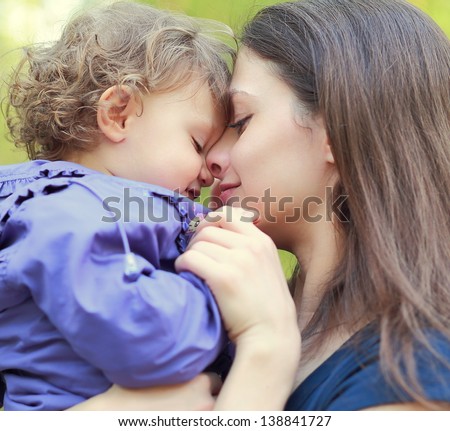 Loving mother holding small happy girl and smiling. Closeup portrait face at face