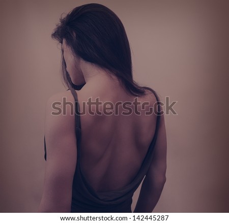 Beautiful woman in dress with naked back and long hair on dark background