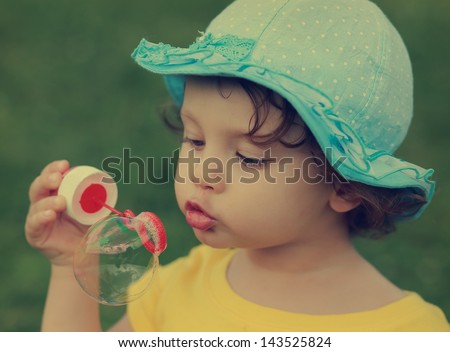 Cute child blowing big bubble. Closeup vintage portrait