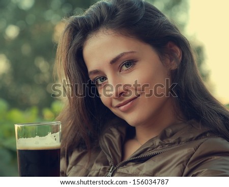 Beautiful woman drinking dark beer outdoor. Closeup portrait